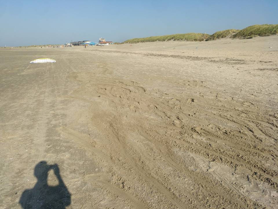 Beach with skid marks made by feet dragging through sand.