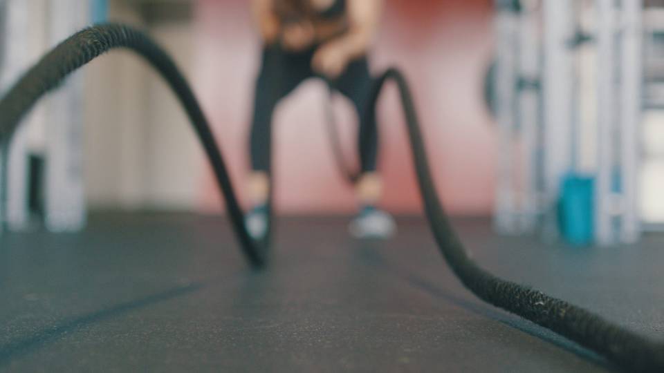 Out of focus image of woman working out with battle ropes.