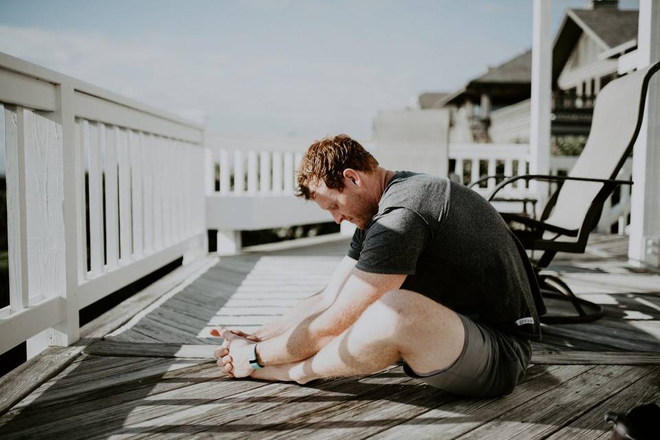 Man doing stretches on a porch or balcony.