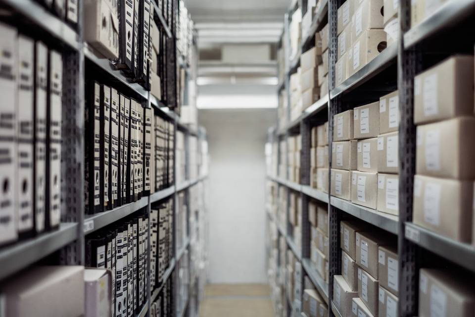 Two rows of cabinets with boxes filled with files or documents.